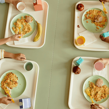 Bambini a mensa che mangiano dai loro vassoi