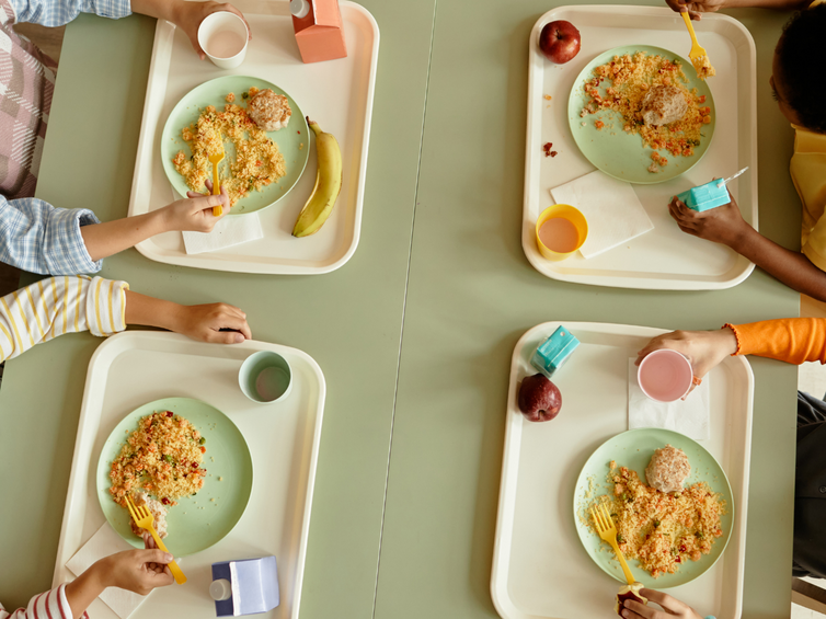 Bambini a mensa che mangiano dai loro vassoi