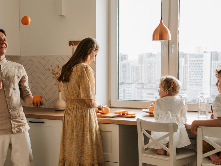 famiglia in cucina luminosa, mamma e papà cucinano per i bambini giocando