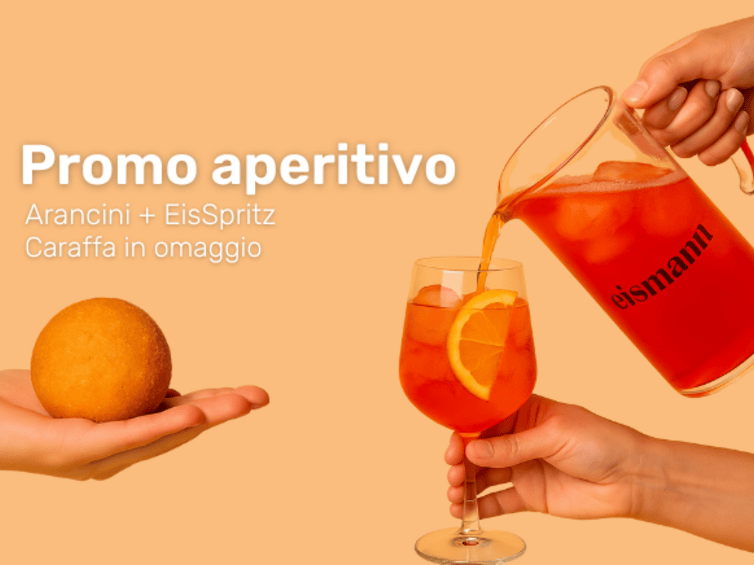 Mano che sorregge l'arancino, mano che versa lo spritz nel calice