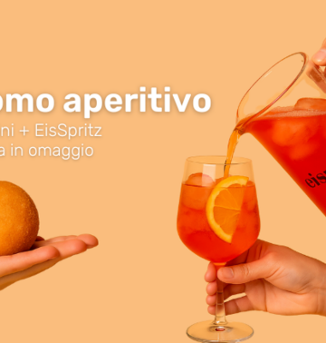 Mano che sorregge l'arancino, mano che versa lo spritz nel calice