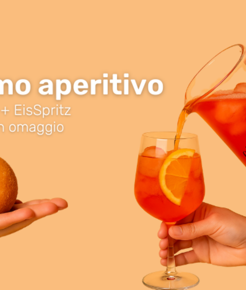 Mano che sorregge l'arancino, mano che versa lo spritz nel calice