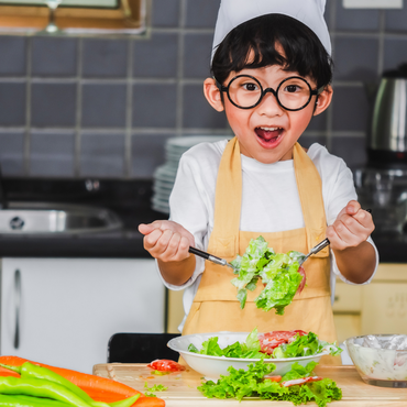 Bambino che prepara verdure colorate in cucina, esempio di alimentazione sana per bambini.