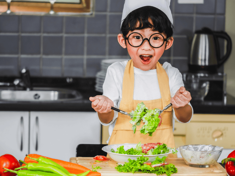 Bambino che prepara verdure colorate in cucina, esempio di alimentazione sana per bambini.